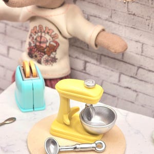 マイレグサイズのプレイフード...黄色のスタンドミキサー、ボウル、ハンドタオルで飾ったミニチュアドールハウスクリスマス。小さなネズミの服のクリスマスエルフ