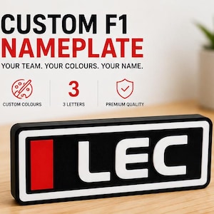 May include: A rectangular black nameplate featuring a white border and the white letters LEC next to a red vertical rectangle. The text above reads CUSTOM F1 NAMEPLATE, YOUR TEAM. YOUR COLOURS. YOUR NAME. with icons for custom colours, 3 letters, and premium quality.