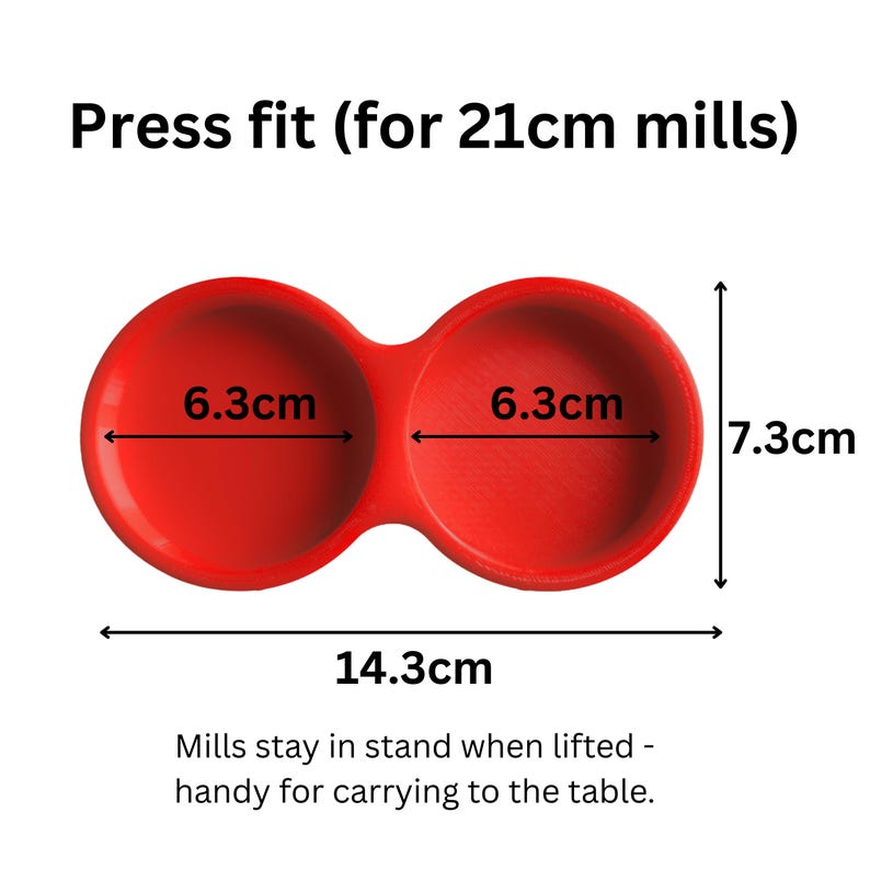 May include: A red double-cup holder for 21cm mills with a press fit design. The unit measures 14.3cm in total width and 7.3cm in height, with each cup having a 6.3cm diameter. The text reads: Press fit (for 21cm mills) and Mills stay in stand.