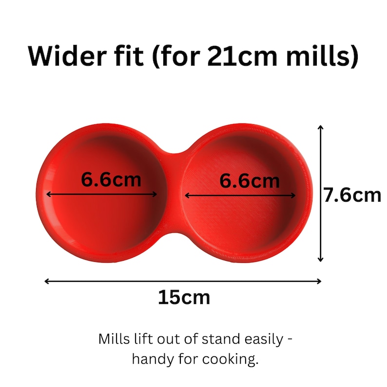 May include: A red double-holder stand for mills with a wider fit. The unit measures 15cm in total width and 7.6cm in height, with two circular openings each 6.6cm in diameter. Text reads: Wider fit (for 21cm mills) and Mills lift out of stand easily.