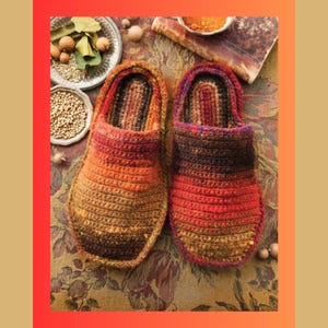 Puede incluir: Un par de zapatillas de crochet con un patrón de rayas multicolores en tonos marrones, naranjas, rojos y morados. Las zapatillas están hechas con un hilo grueso y tienen un diseño simple de poner y quitar.