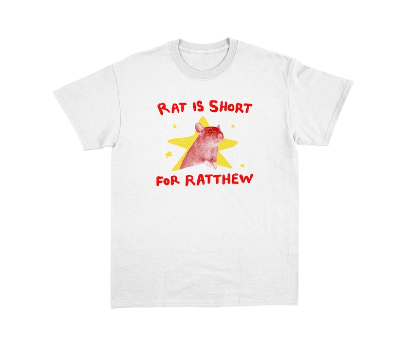 May include: White t-shirt with a graphic design featuring a red rat inside a yellow star. The text above the rat reads "RAT IS SHORT" and below it, "FOR RATTHEW" in red. The shirt is made of a soft material.