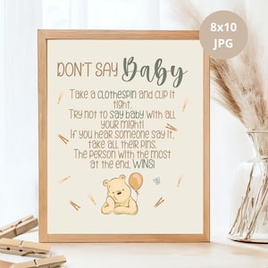 Pode incluir: Um cartão de jogo imprimível de 20,3 x 25,4 cm com uma ilustração do Winnie the Pooh e o texto "DON'T SAY Baby. Take a clothespin and CLIP it tight. Try not to say baby with ALL YOUR Might! If you hear someone say it, take all their PINS. The person with the most at the end, WINS!"
