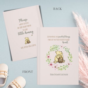 Op de afbeelding: Een roze baby shower gastenboek met een Winnie de Poeh-illustratie. De voorkant heeft de tekst "Schrijf alstublieft een berichtje of teken je naam, zodat onze kleine honingbij weet dat je er was." De achterkant heeft de tekst "Soms nemen de kleinste dingen de meeste ruimte in je hart in."