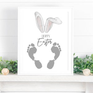 May include: A white framed print with a gray footprint design and the text "Hoppy Easter". Watercolor bunny ears are at the top of the print.