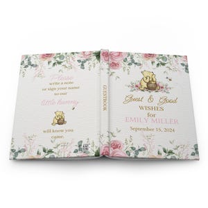 May include: A Winnie the Pooh themed guest book with a floral design. The cover features a pink floral pattern with a Winnie the Pooh illustration holding a honey pot. The text on the cover reads "Guest & Good Wishes for Emily Miller September 15, 2024".