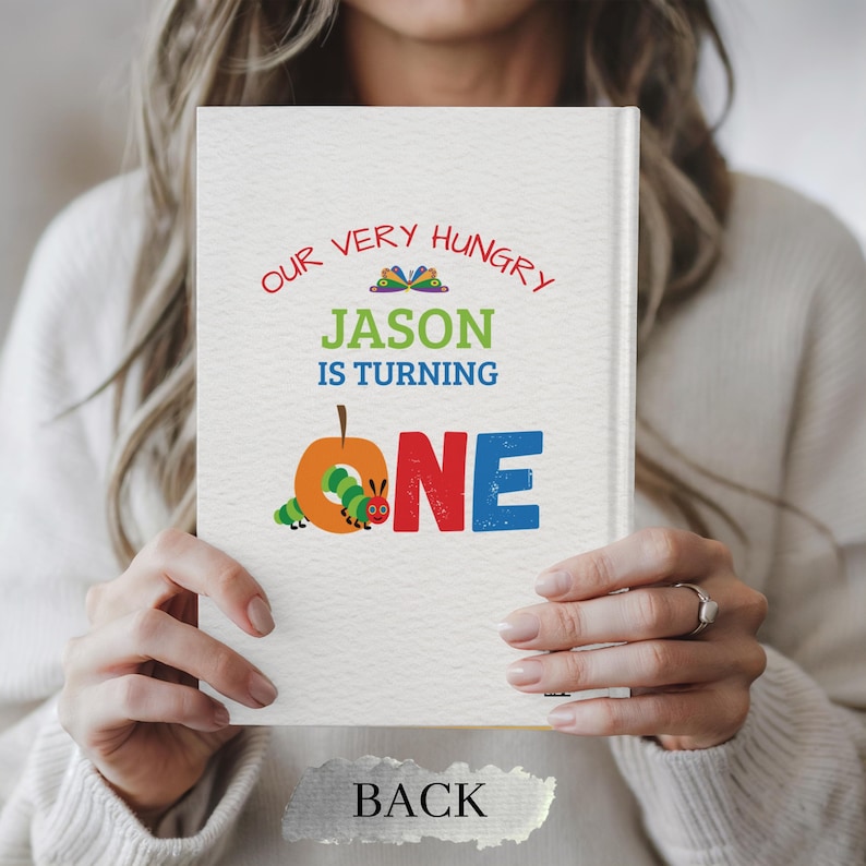 May include: A personalized book cover with the text "OUR VERY HUNGRY JASON IS TURNING ONE." The design features a colorful caterpillar and apple illustration. The word "BACK" is printed at the bottom of the book.