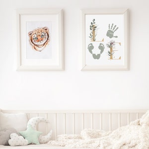 May include: Two framed prints, one with a watercolor illustration of a tiger cub and the other with a handprint and footprints forming the word "LOVE" with floral accents.