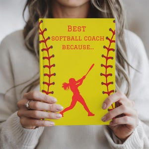 May include: Yellow journal with red stitching around the edges. The journal has a red silhouette of a softball player and the text "BEST SOFTBALL COACH BECAUSE..."