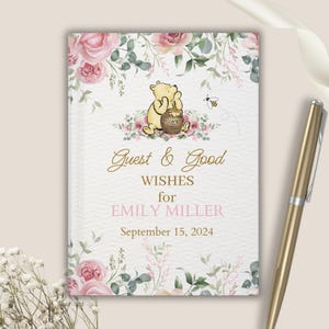 May include: A Winnie the Pooh themed guest book with a floral design. The cover features Winnie the Pooh holding a honey pot with the text "Guest & Good Wishes for Emily Miller September 15, 2024".
