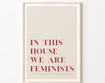 May include: A beige poster with the text "IN THIS HOUSE WE ARE FEMINISTS" printed in red.