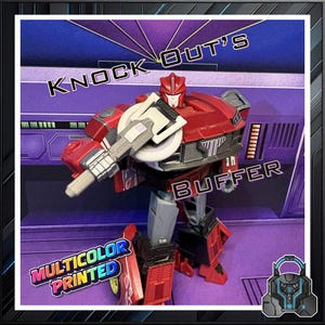 May include: A red and gray robot toy with the text "KNOCK OUT'S BUFFER" and "MULTICOLOR PRINTED". The robot has a shield-like weapon and is set against a purple and blue background.