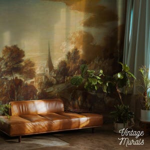 May include: A brown leather sofa with a tufted design sits in front of a large mural depicting a vintage landscape scene. The mural features a church steeple and trees. The words "Vintage Murals" are in the bottom right corner.