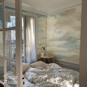 Può includere: Una camera da letto con un murale di nuvole sulla parete, un letto con biancheria da letto bianca e un tavolino con un vaso di fiori. La stanza ha una finestra con tende bianche. Il testo "Vintage Murals" è visibile in basso a sinistra.