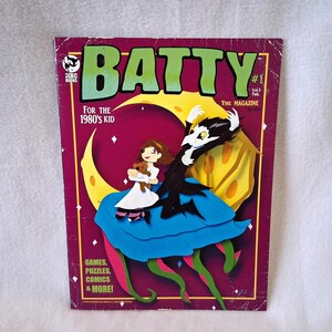 May include: A vintage "Batty" magazine cover with a purple border. The cover features a cartoon illustration of a girl with a teddy bear, a bat-like creature, and the text "BATTY" in green. The magazine is labeled "#1" and "For the 1980's Kid."