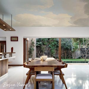 May include: A modern dining room with a large wooden table and chairs. The ceiling features a mural of a cloudy sky. Large glass doors open to a lush green garden, creating a bright and airy space. The floor is a glossy white.