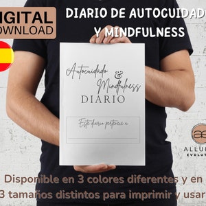 Puede incluir: Un diario blanco imprimible con el texto "Autocuidado & Mindfulness DIARIO" y "Este diario pertenece a". El diario está siendo sostenido por una persona que lleva una camiseta negra. El texto "DIGITAL DOWNLOAD" y "DIARIO DE AUTOCUIDADO Y MINDFULNESS" es visible en la parte superior de la imagen. El texto "Disponible en 3 colores diferentes y en 3 tamaños distintos para imprimir y usar." es visible en la parte inferior de la imagen.