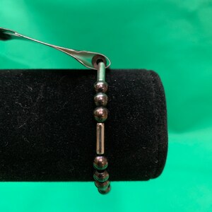 May include: A silver bracelet with black beads and silver spacers.
