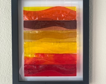 Vibrant fused glass with warm hues reminiscent of a sunset.