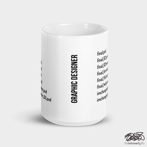 Op de afbeelding: Witte keramische koffiemok met zwarte tekst die "GRAPHIC DESIGNER" aan de zijkant staat en een lijst met bestandsnamen die betrekking hebben op grafisch ontwerp aan de rechterkant.