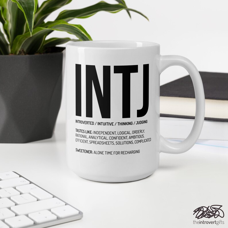 May include: White ceramic mug with a black graphic of the letters INTJ and the text "INTROVERTED/INTUITIVE/THINKING/JUDGING" and "TASTES LIKE: INDEPENDENT, LOGICAL, ORDERLY. RATIONAL, ANALYTICAL, CONFIDENT. AMBITIOUS, EFFICIENT. SPREADSHEETS. SOLUTIONS. COMPLICATED. SWEETENER: ALONE TIME FOR RECHARGING".