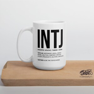 May include: White ceramic mug with a black graphic of the letters INTJ and the text "INTROVERTED/INTUITIVE/THINKING/JUDGING" and "TASTES LIKE: INDEPENDENT, LOGICAL, ORDERLY, RATIONAL, ANALYTICAL, CONFIDENT, AMBITIOUS, EFFICIENT, SPREADSHEETS, SOLUTIONS, COMPLICATED" and "SWEETENER: ALONE TIME FOR RECHARGING".
