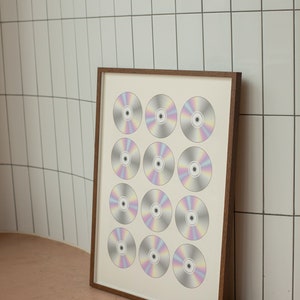 K&ouml;nnte beinhalten: Ein gerahmter Druck einer Gitterstruktur aus 12 schillernden CDs, jede mit einem einzigartigen Regenbogenmuster. Der Rahmen ist aus braunem Holz und der Hintergrund ist wei&szlig;.