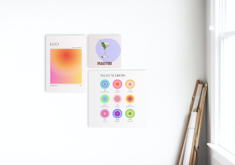 May include: Three colourful prints on a white wall. The first print is a gradient of pink, orange, and yellow with the word "LEO" at the top. The second print is a light blue background with a martini glass and the word "MARTINI" at the bottom. The third print is a light green background with the words "ANGEL NUMBERS" at the top and nine colourful circles with numbers inside.