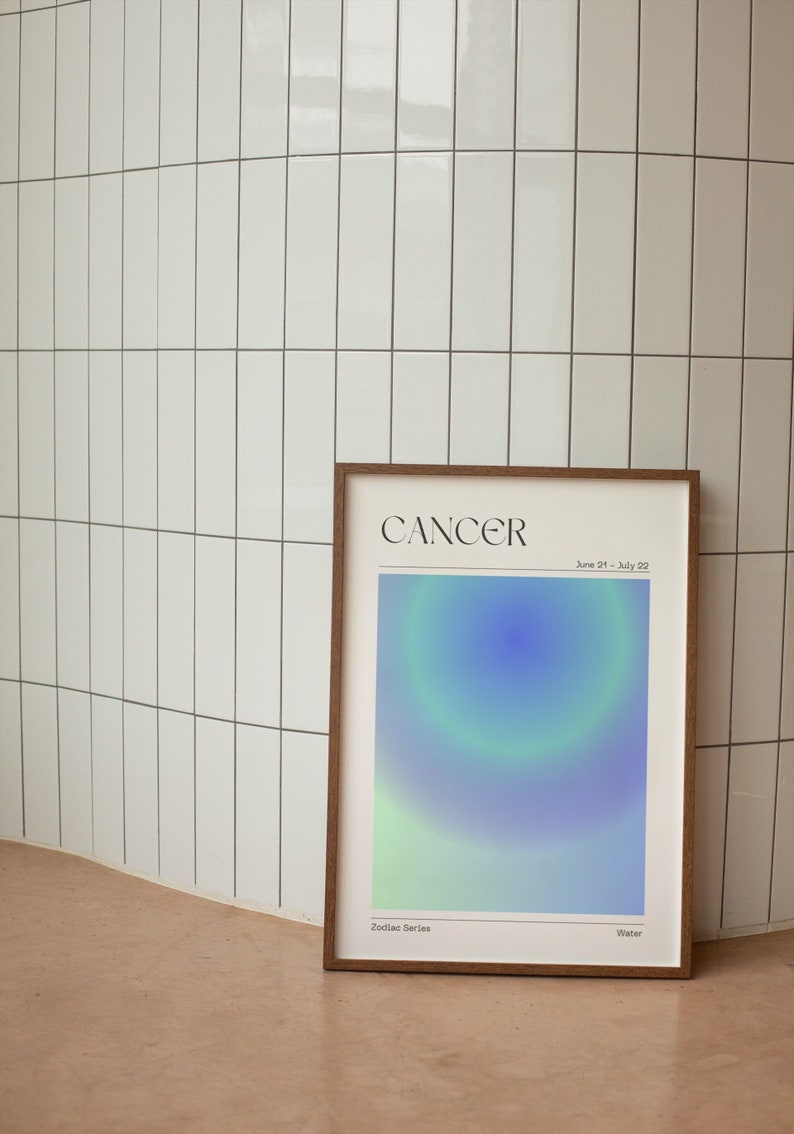 May include: A framed print with a blue, green, and white gradient design. The print features the text "Cancer" and "June 21 - July 22" at the top. The bottom of the print reads "Zodiac Series" and "Water".