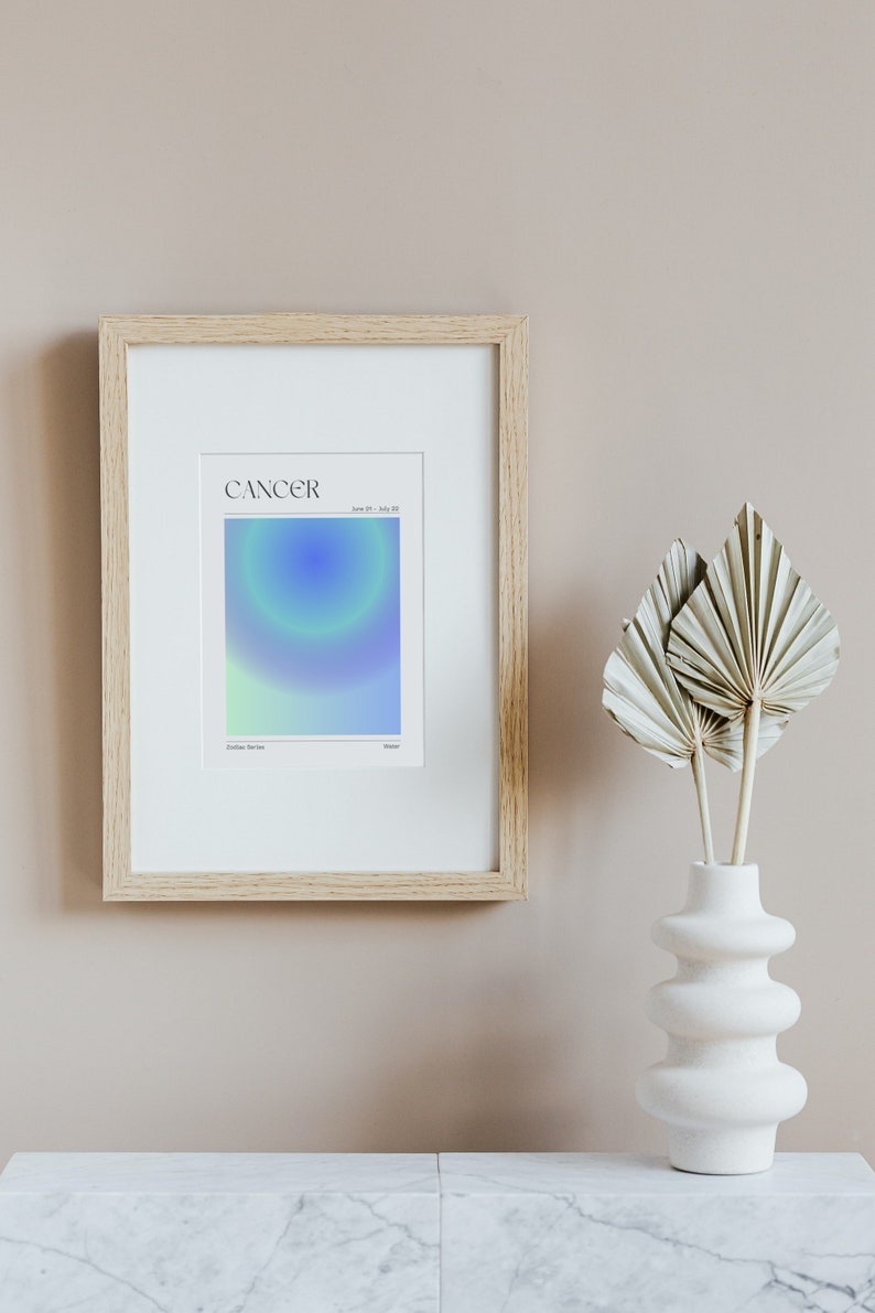 May include: A framed print with a light blue, green, and white gradient design. The print has the word "CANCER" in black text at the top and the dates "June 21 - July 22" in smaller black text below. The words "Zodiac Sign" and "Water" are in smaller black text at the bottom of the print.