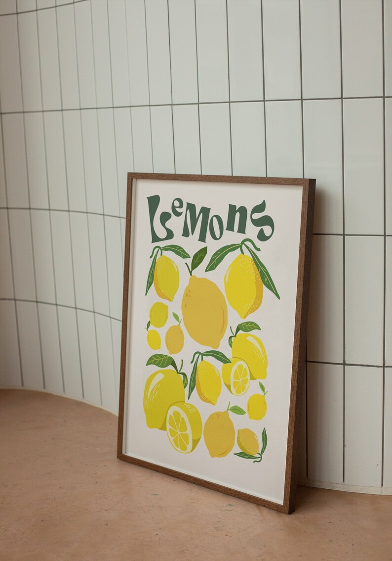 May include: A framed print with the text "Le Mons" in green lettering and a white background. The print features a cluster of yellow lemons with green leaves.