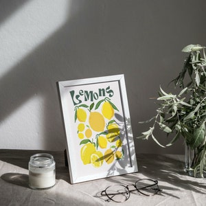 May include: A white framed print with the word "Lemons" in green lettering and a colorful illustration of lemons on a white background.