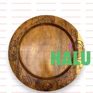 Puede incluir: Una bandeja redonda de madera para servir con un diseño decorativo. La bandeja tiene un acabado de madera marrón oscuro y presenta un patrón geométrico con un diseño de sol, luna y cruz.