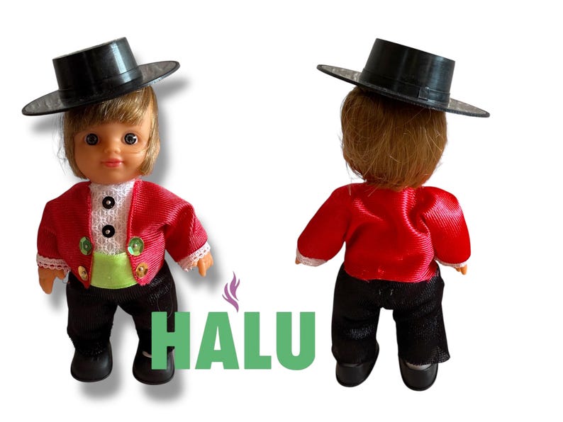 May include: Two small dolls in traditional dress. Each doll wears a black hat, red jacket, black trousers, and black shoes. One doll faces forward, and the other faces away. The dolls are on a white background.