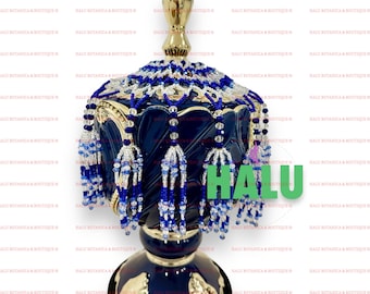 Puede incluir: Un quemador de incienso de cerámica azul y dorado con una franja de cuentas decorativas. La franja está hecha de cuentas azules y blancas y tiene una apariencia de borla. El quemador tiene un borde dorado y un diseño decorativo.