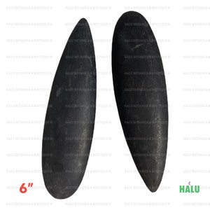 Op de afbeelding: Twee zwarte, gladde, ovaalvormige massagestenen, elk ongeveer 15 cm lang. De stenen hebben een afgerond uiteinde en een taps toelopende punt. De afbeelding bevat de tekst "HALU BOTANICA & BOUTIQUE".