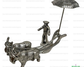Peut inclure: Une figurine en métal argenté représentant un fermier conduisant une paire de bœufs tirant une charrue. Le fermier porte un chapeau et tient les rênes. Les bœufs tirent une charrue avec un parapluie en métal argenté au-dessus d'eux.