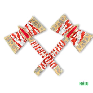 May include: Two decorative axes with red, white, and gold beadwork. The axe heads feature a leopard print design and are adorned with seashells. The handles are wrapped in alternating red and white beads, with seashells.