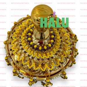 May include: A gold decorative bowl with a round top and a beaded design. The bowl is decorated with yellow and purple beads.