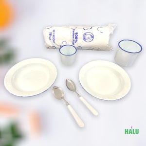 May include: A set of white enamelware dishes with blue trim, including two bowls, two mugs, and two spoons. The spoons have white handles. A white cotton roll is also included.