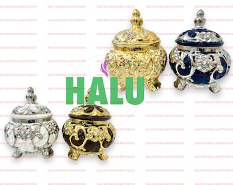 Pode incluir: Quatro recipientes de cerâmica decorativos com tampas. Os recipientes são dourados, prateados e azuis com desenhos florais intrincados e pedrarias. Os recipientes estão sobre um fundo branco.