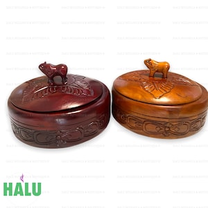 May include: Two wooden boxes with carved lids and animal finials. The box on the left is dark brown with a carved floral design. The box on the right is light brown with a carved leaf design. Both boxes have a carved animal finial on the lid.