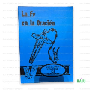 Peut inclure: Un livre bleu intitulé "La Fe en la Oración" avec une illustration noire d'une croix et d'un chapelet. La couverture comprend également le texte "Este Libro Contiene 132 Oraciones".
