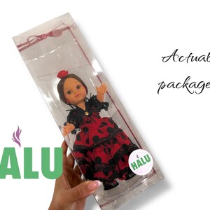 May include: A doll in a clear plastic package. The doll is wearing a red dress with black polka dots and lace trim. The doll has brown hair and a red flower in her hair. The package has the text "Actual package!" and a logo that says "HALU".