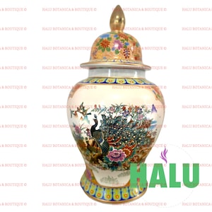 May include: A decorative ceramic vase with a lid, featuring a peacock design. The vase has a cream-colored base with colorful floral and bird illustrations. The lid is gold with floral patterns. The base has a decorative pattern.