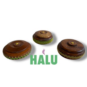 Könnte beinhalten: Drei Holzkisten mit Deckeln. Die Kisten sind braun mit goldenen Akzenten und grünen Verzierungen. Das Wort "HALU" ist darunter in Grün gedruckt.