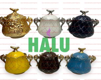 Pode incluir: Uma coleção de açucareiros decorativos de cerâmica em várias cores, incluindo dourado, branco, azul marinho, amarelo, castanho e azul. Cada tigela apresenta um design padronizado, alças ornamentadas e uma tampa com um botão decorativo. A palavra "HALU" é exibida em verde.