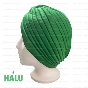 May include: A green turban with a quilted design. The turban is on a white mannequin head.