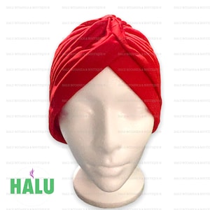 May include: A red turban style head wrap made of fabric. The wrap is folded and twisted to create a unique design.