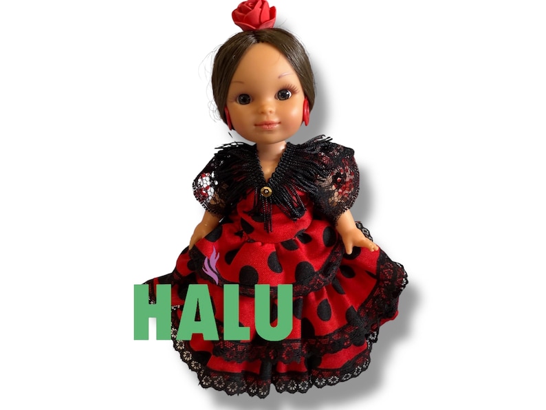 May include: A doll wearing a red dress with black polka dots and black lace trim. The doll has brown hair, red earrings, and a red rose in her hair. The word "HALU" is printed in green on the dress.
